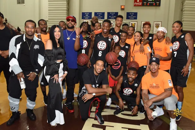 A group of people on a basketball court holding basketballs and wearing athletic clothes.