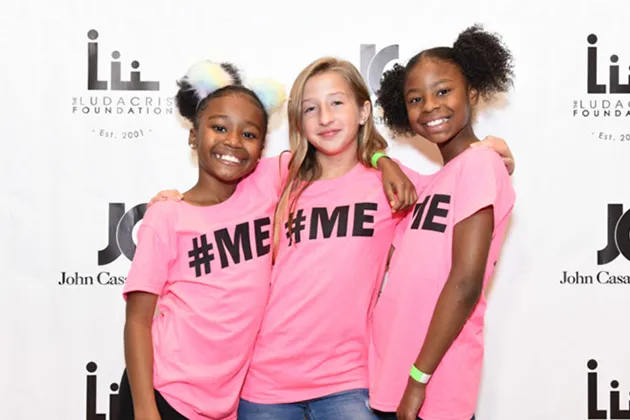 Three girls wearing pink t-shirts that read '#ME'. 