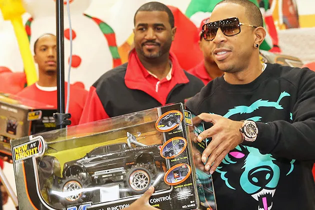 Chris 'Ludacris' Bridges hands a toy truck to someone standing offscreen.